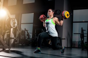 Fit young woman lifting barbells looking focused, working out in a gym Fit young woman lifting barbells looking focused, working out at a gym